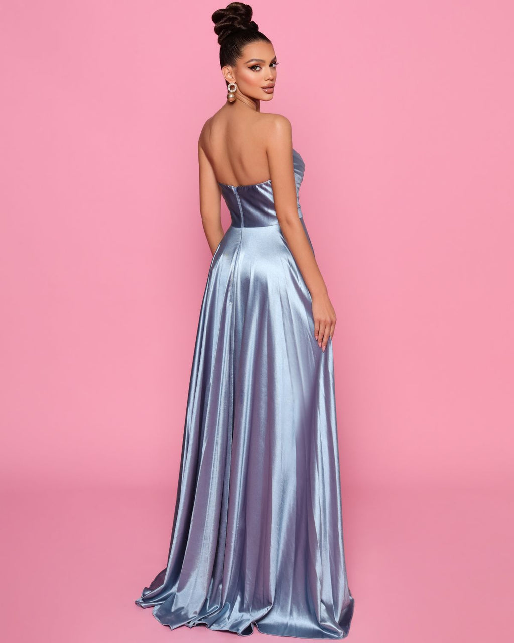 Woman wearing a strapless silver gown against a pink background