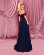 Woman in a navy blue evening gown standing against pink draped curtains.