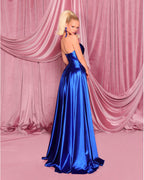 Woman in a blue evening gown standing against a pink curtain backdrop