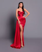 Woman wearing a red evening gown with a slit on a gray background