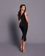 Woman wearing a black dress with a slit on a gray background