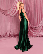 Woman in a green evening gown standing against a pink draped curtain backdrop