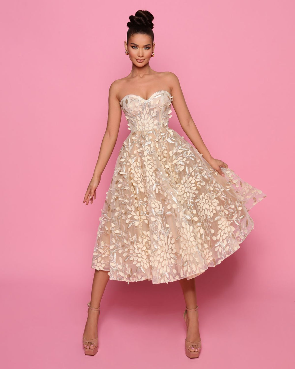 Woman wearing a strapless floral dress against a pink background