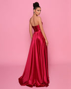 Woman wearing a red satin gown against a pink background