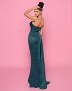 Woman in a teal strapless gown against a pink background