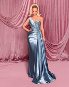 Woman in a silver evening gown standing against a pink curtain backdrop