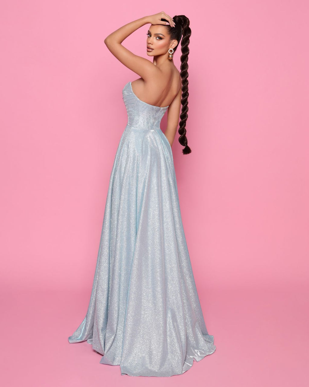 Woman in a silver evening gown against a pink background