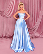 Woman in a strapless blue gown against a pink curtain backdrop