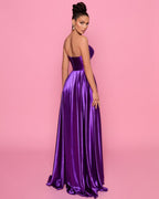 Woman wearing a purple evening gown against a pink background