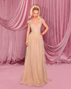 Woman in a beige evening gown against a pink curtain backdrop