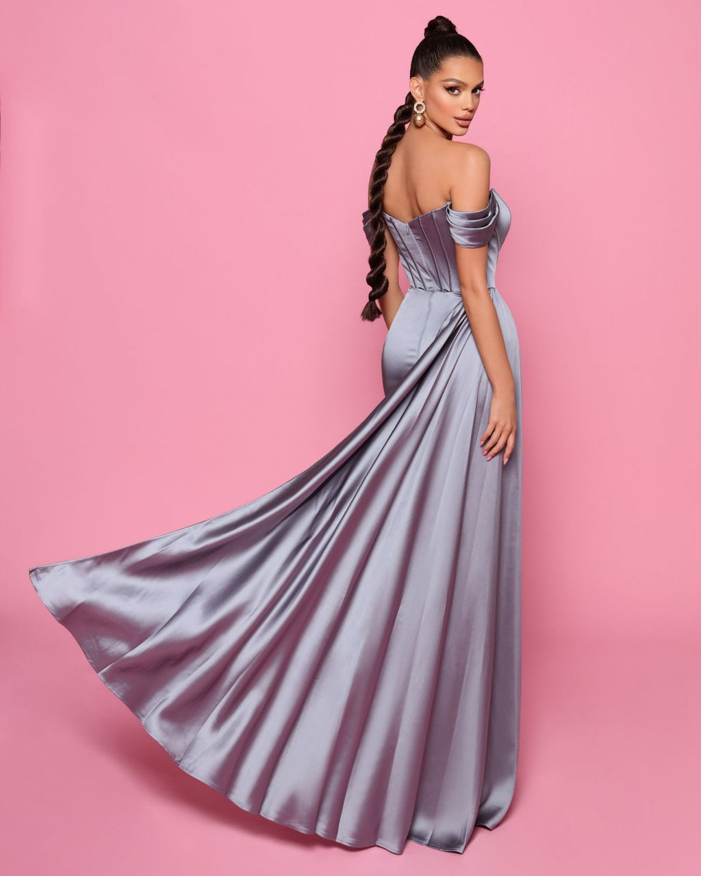 Woman in a strapless silver gown on a pink background