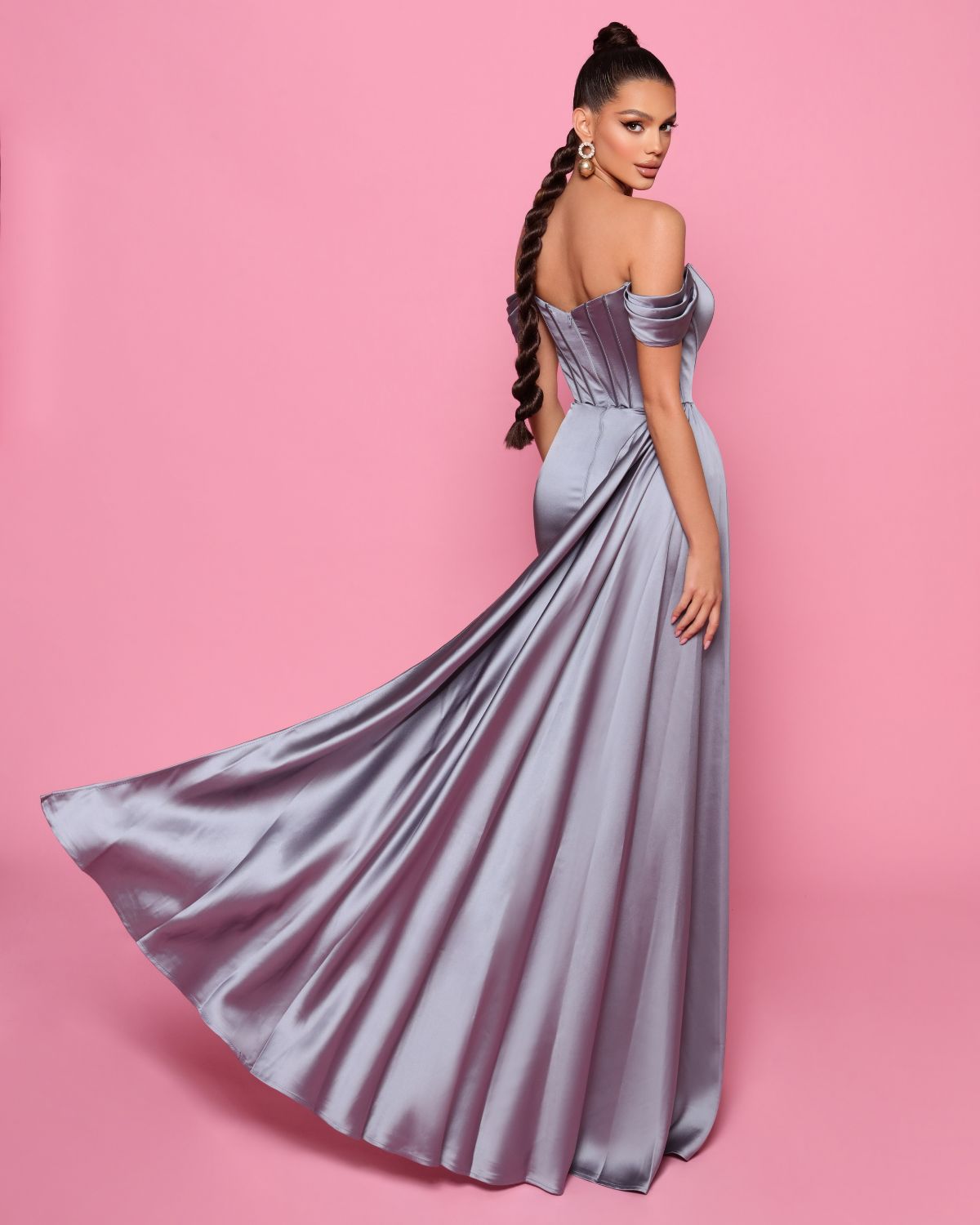 Woman in a strapless silver gown on a pink background