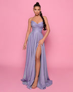Woman wearing a purple strapless gown with a high slit on a pink background