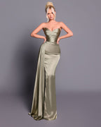 Woman wearing a strapless, floor-length green gown against a gray background