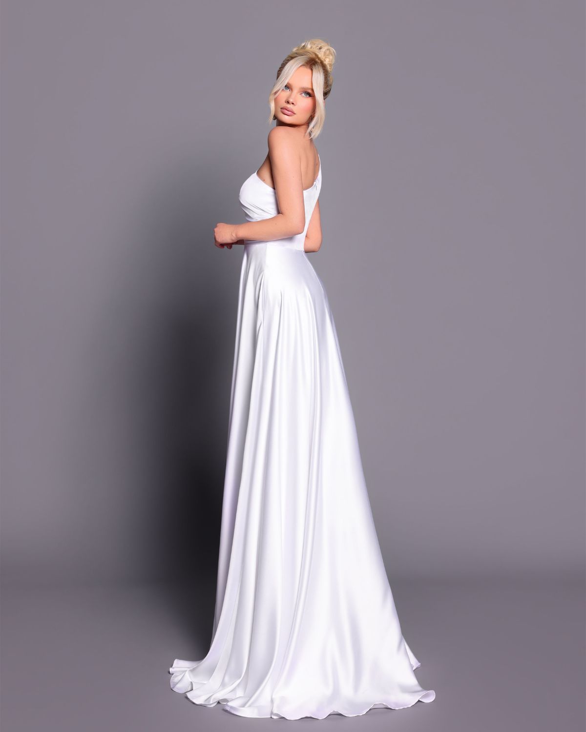 Woman wearing a white gown against a gray background