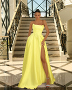 Woman in a bright yellow strapless gown with a high slit standing on a staircase.