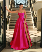Woman in a pink strapless gown with a high slit standing on a staircase.