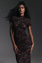 Woman wearing a dark lace dress against a gray background