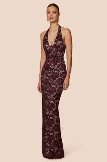 Woman wearing a dark purple lace evening gown on a beige background