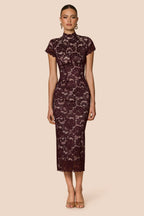 Woman wearing a dark lace dress on a beige background