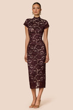 Woman wearing a dark lace dress on a beige background