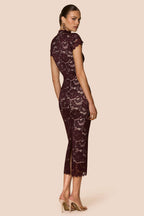 Woman wearing a dark lace dress on a beige background