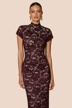 Woman wearing a dark lace dress against a beige background
