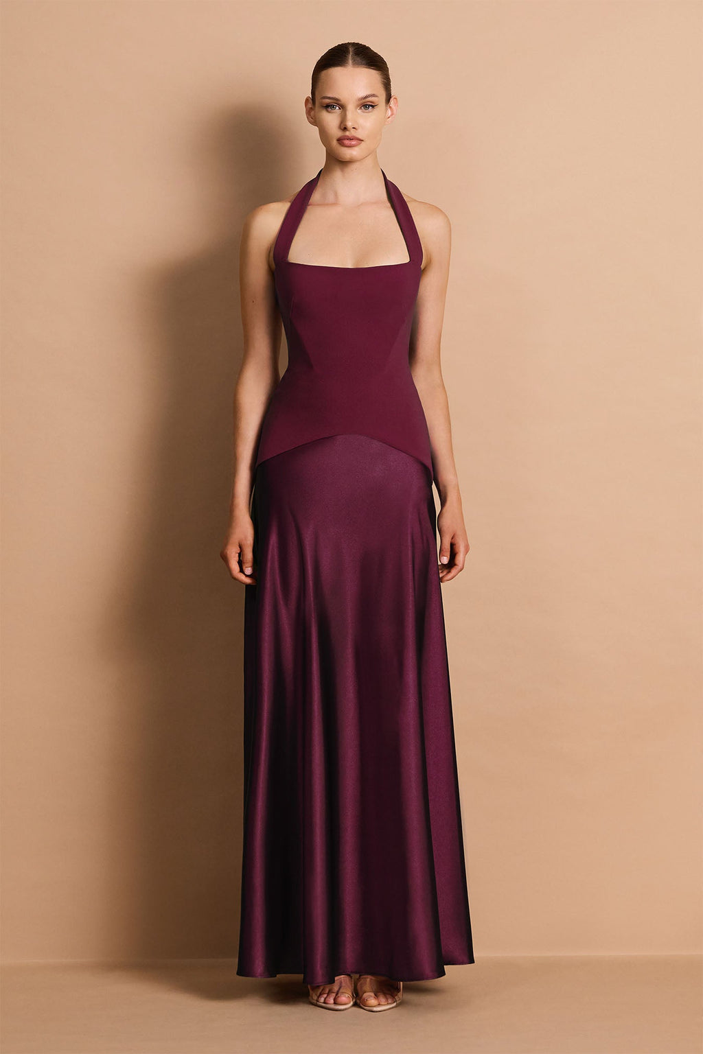 Woman wearing a long burgundy dress against a beige background
