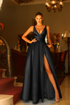 Woman in a black evening gown with a high slit standing in an elegant room.