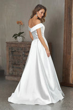 Woman wearing a white off-shoulder dress in an indoor setting.