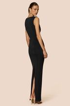 Woman wearing a black sleeveless evening gown with a high slit on a beige background