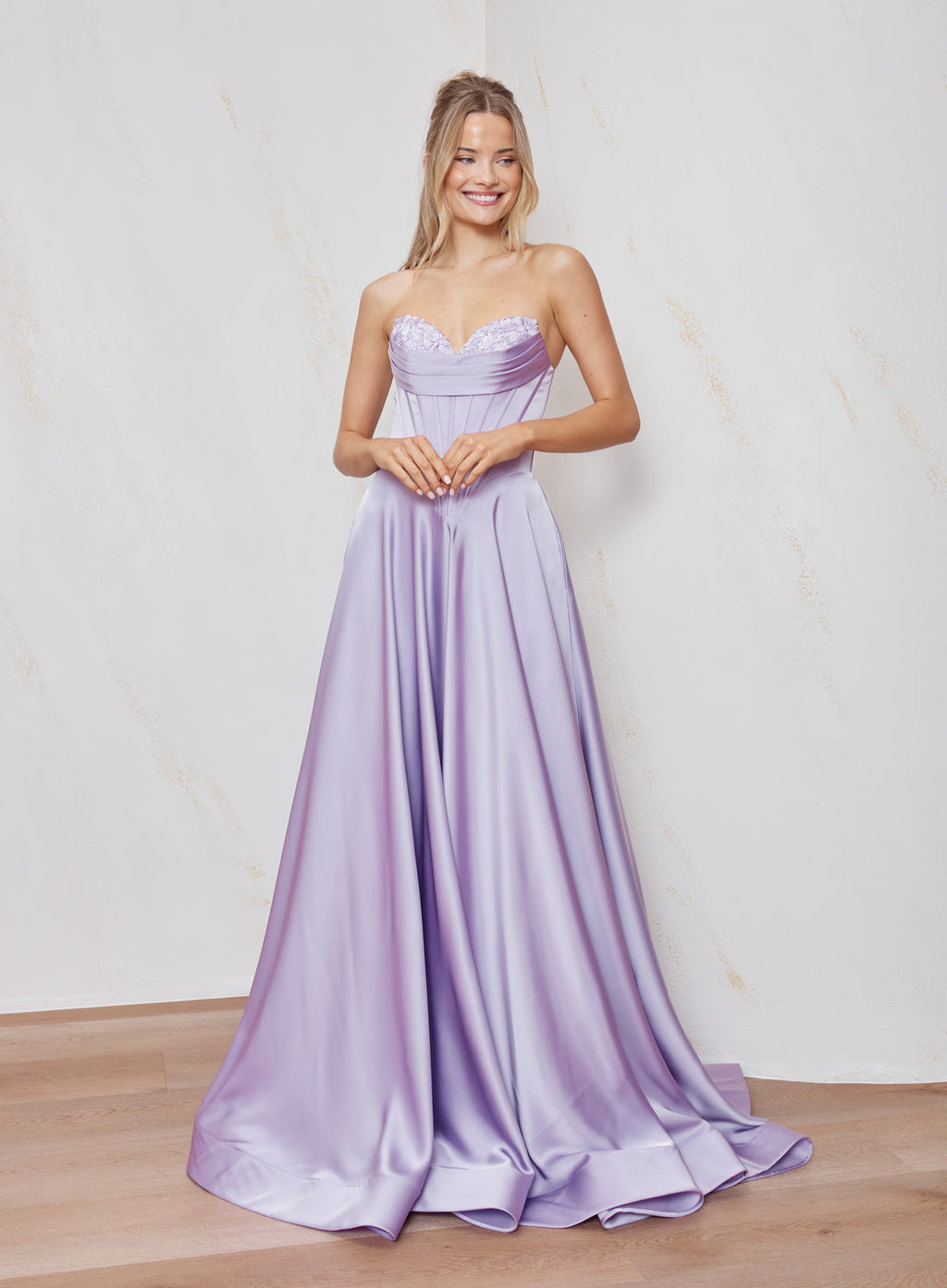 Woman wearing a strapless lavender gown against a plain background