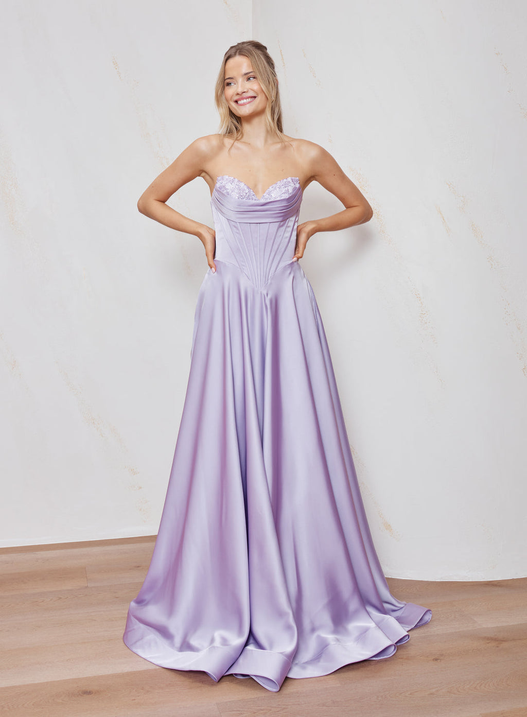 Woman wearing a strapless lavender gown against a plain background