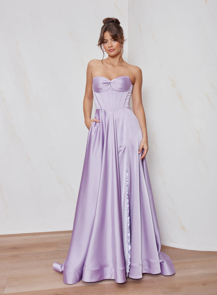 Woman wearing a strapless lavender gown with a plain background