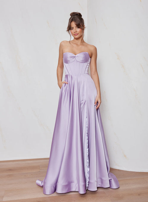 Woman wearing a strapless lavender gown with a plain background