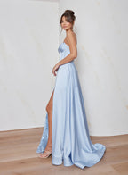Woman wearing a light blue strapless gown with a high slit on a plain background