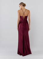 Woman wearing a burgundy evening gown with a backless design on a white background