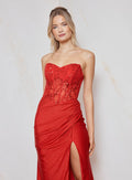 Woman wearing a red strapless gown with a slit on a light background