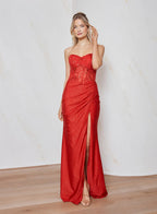 Woman wearing a red strapless gown with a slit on a white background