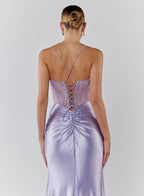 Woman wearing a lavender evening gown with a lace-up back on a plain background