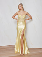Woman wearing a gold evening gown with a high slit on a wooden floor.