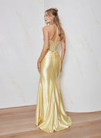 Woman wearing a gold evening gown against a white wall.