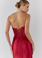 Woman wearing a red dress with a lace-up back on a white background