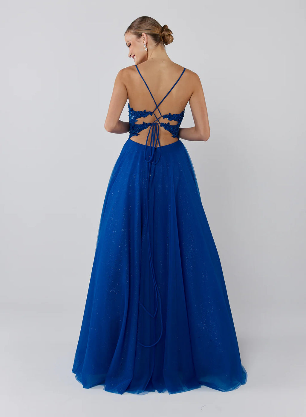 Woman wearing a blue evening gown with a lace-up back on a white background