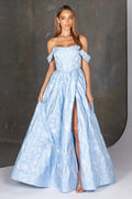 Woman wearing a light blue off-shoulder gown with a slit on a dark background