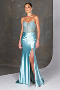 Woman wearing a light blue evening gown with a high slit on a neutral background