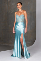 Woman wearing a light blue evening gown with a high slit on a neutral background
