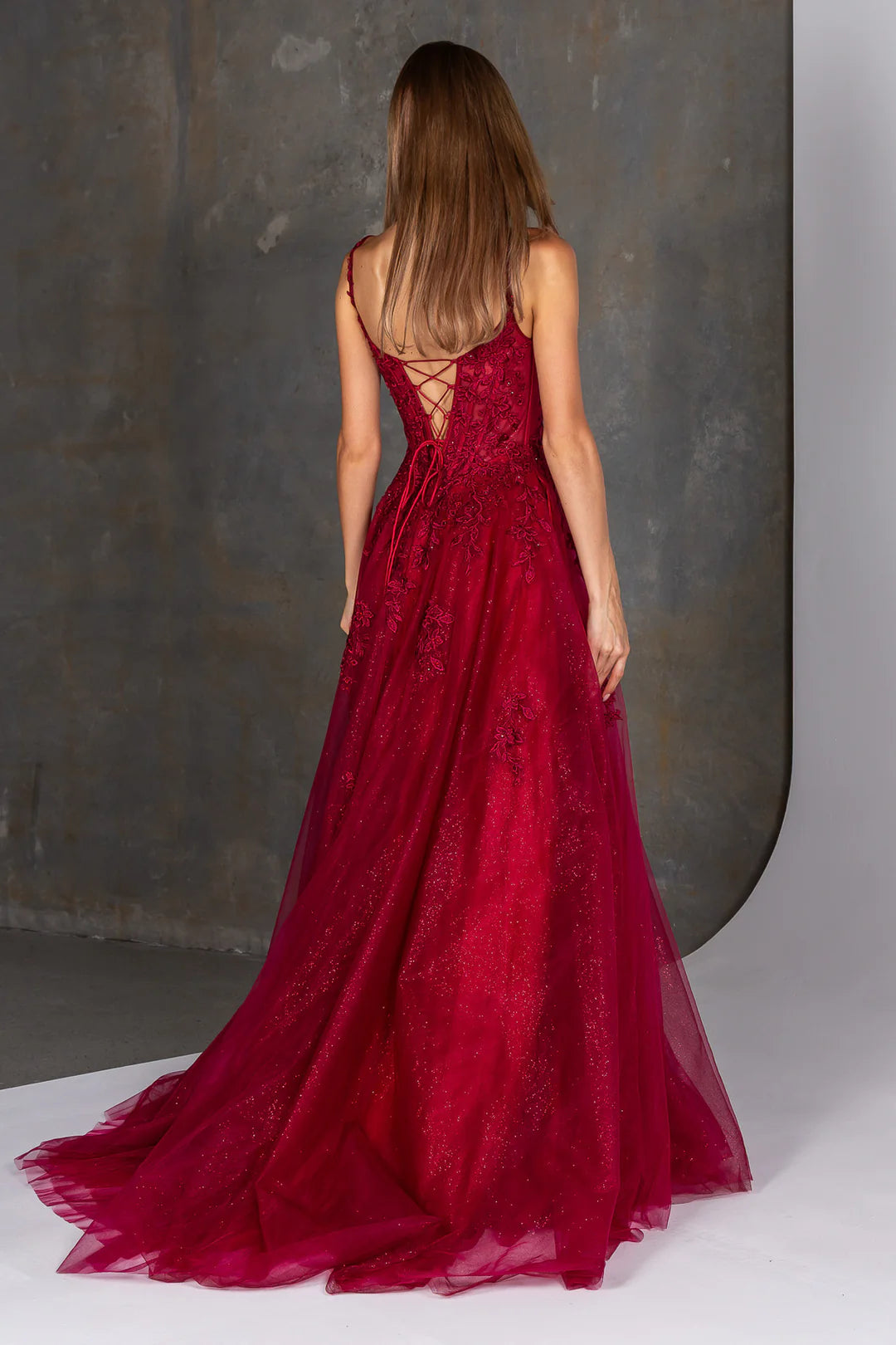 Red lace evening gown with a backless design on a neutral background