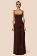 Woman wearing a brown pleated dress against a beige background