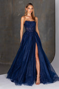 Woman wearing a navy blue evening gown with a slit on a gray background